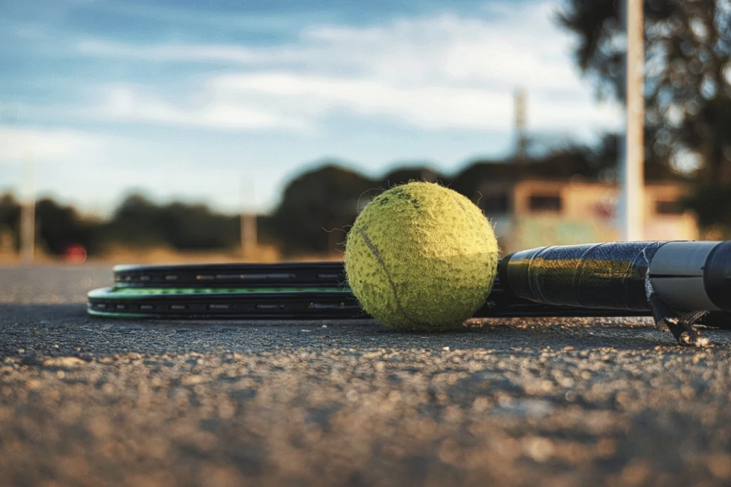 Tennis racket and ball on the asphalt